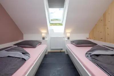 two beds in a attic bedroom with a window at Pr `Agotnik Apartments & Rooms Bohinj in Bohinj