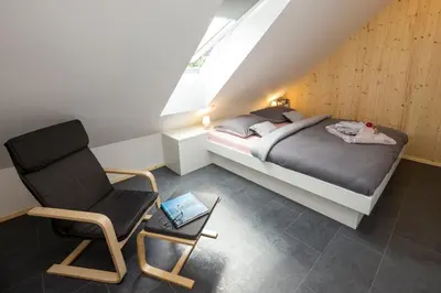 a bedroom with a bed and a chair in a attic at Pr `Agotnik Apartments & Rooms Bohinj in Bohinj