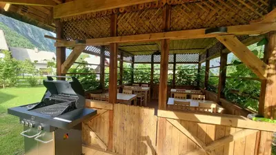 a wooden pavilion with tables and a stove in it at Pr `Agotnik Apartments & Rooms Bohinj in Bohinj