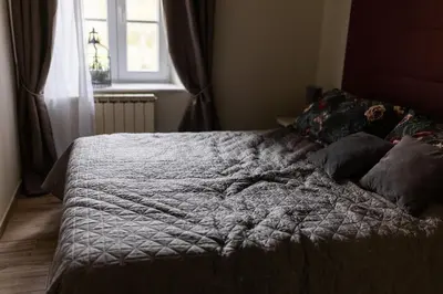 a bed with a gray comforter and a window at Villa Xaxat in Koper