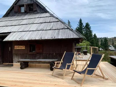 two chairs and a bench in front of a building at Chalet Neza Velika Planina in Stahovica