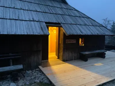a wooden building with a bench on a deck at Chalet Neza Velika Planina in Stahovica