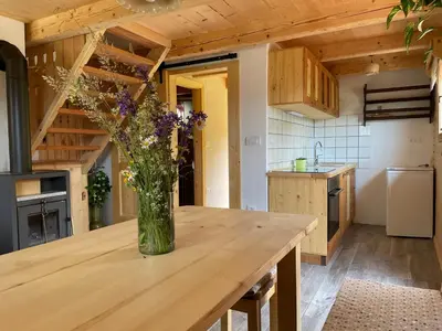 a vase of flowers on a wooden table in a kitchen at Miha`s cottage in Bohinj