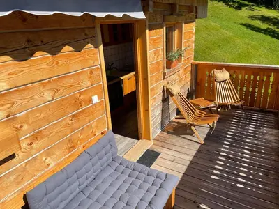 a porch with a bench and two chairs on a deck at Miha`s cottage in Bohinj
