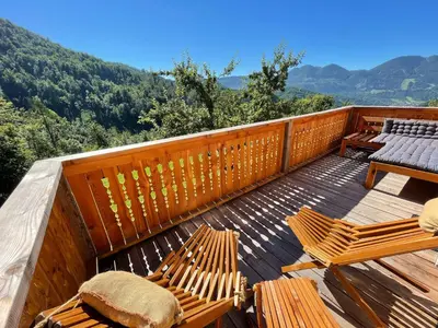 a deck with two chairs and a table on it at Miha`s cottage in Bohinj