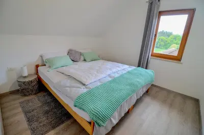 a large bed in a room with a window at Flower house Podčetrtek in Podčetrtek