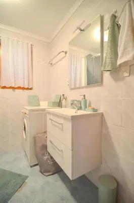 a white bathroom with a sink and a mirror at Flower house Podčetrtek in Podčetrtek