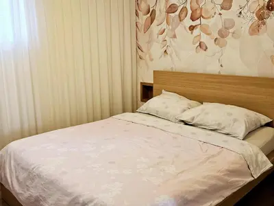 a bed in a bedroom with a flowery wall at Apartma Kras in Komen