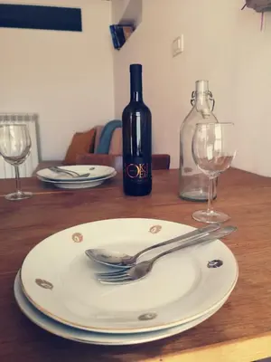 a plate with a fork and a bottle of wine at Apartma Kras in Komen