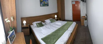 a bedroom with a bed with a green blanket on it at Restavracija in prenočišča ČARDA in Martjanci