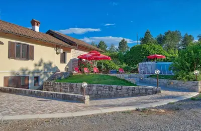 a house with two red umbrellas in a yard at Počitniška hiša Miklavčič Primorska in Divača
