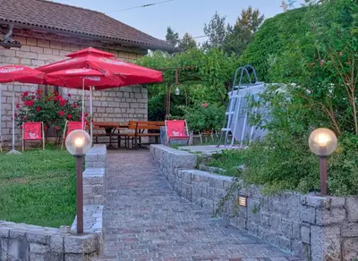 a patio with red umbrellas and a table and chairs at Počitniška hiša Miklavčič Primorska in Divača