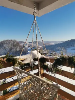 a swing hanging from a porch with snow at Wooden fairytale in Lesično