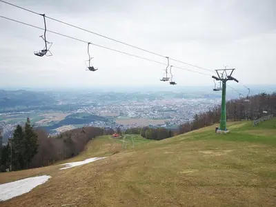 a gondola lift on a hill with a city at Apartma Pohorje Bolfenk 5010 in Pohorje