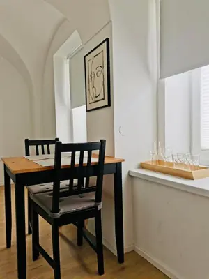 a dining room table with a black chair next to a window at 150 steps to the main square in Ljubljana