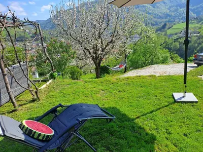a chair and an umbrella on a grass field at Wooden cabin with a view in Idrija