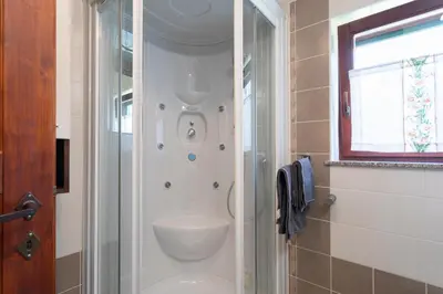 a bathroom with a shower with a sink and a toilet at Tinčeva hiša in Kanal