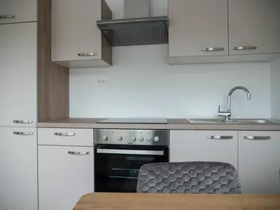 a kitchen with white cabinets and a sink and an oven at Apartments Aura in Deskle