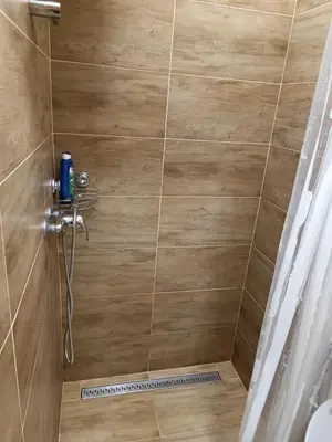 a bathroom with a shower with a wooden wall at Apartments Aura in Deskle