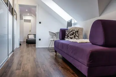 a living room with a purple couch and wooden floors at Celje Center Apartment in Celje