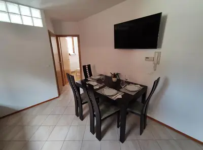 a dining room table with chairs and a television on a wall at Apartments Bohinjc in Bohinj