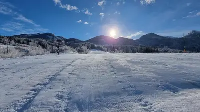 a snow covered road with the sun in the background at Apartments Bohinjc in Bohinj