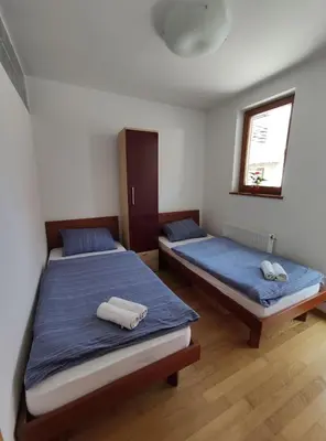 two beds in a room with blue sheets and a window at Apartments Bohinjc in Bohinj