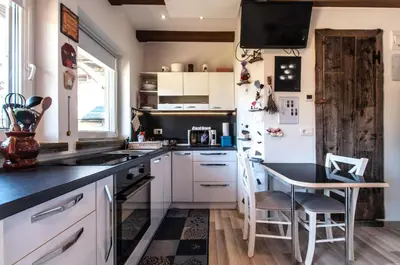 a kitchen with white cabinets and a black counter top at Apartments JULIA Bohinj in Bohinj