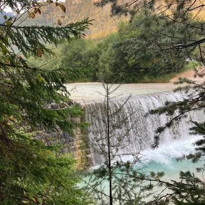 a waterfall on the side of a river with trees at Pri Marusi in Kranjska Gora