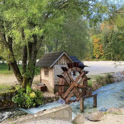 a small house and a watermill next to a river at Pri Marusi in Kranjska Gora