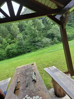 a picnic table with a bench in a field at Apartma Juteršek 2+2 in Libeliče
