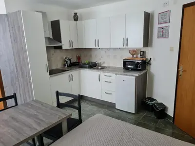 a small kitchen with white cabinets and a table at Apartma Juteršek 2+2 in Libeliče