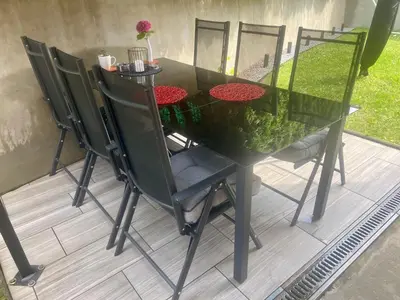 a dining table with four chairs and a black table with a glass top at Jack's Place in Trbovlje