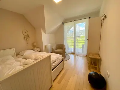 a bedroom with a bed and a chair and a window at House Eden with Mountain Views in Bled