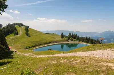 a small tarn on a grassy hill with a mountain at Farmhouse Blackberry Pool & Wellness- Happy Rentals in Vransko
