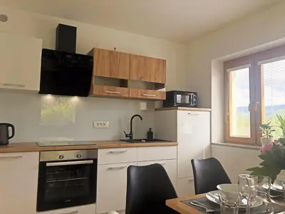 a kitchen with white cabinets and a table with chairs at Apartment Vida in Bled
