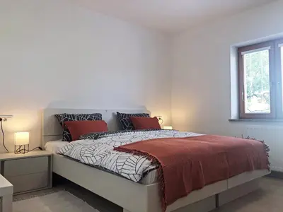 a white bedroom with a large bed with red pillows at Apartment Vida in Bled