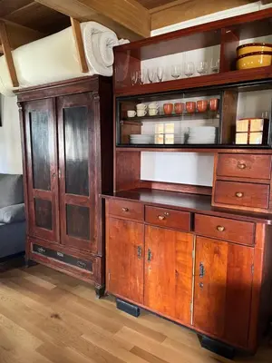 a kitchen with wooden cabinets and a shelf with dishes at Domačija Brdar in Adlešiči