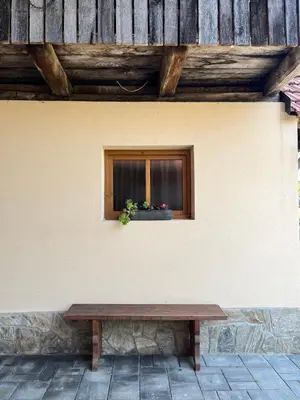 a wooden bench sitting in front of a window at Domačija Brdar in Adlešiči