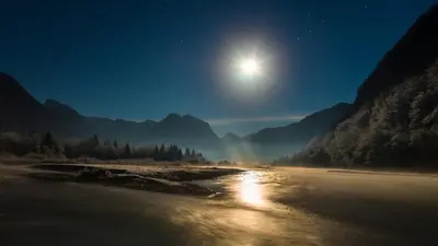 a view of a river at night with the moon at Apartmaji Prton Bovec in Bovec
