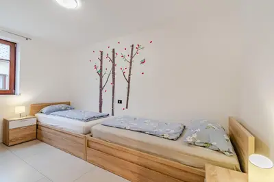 two beds in a room with trees on the wall at Penzion Hosnar, Apartment Mišc in Bovec