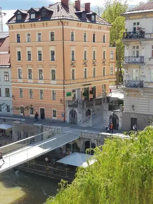 a bridge over a river in front of a building at Above Ljubljanica River Apartment in Ljubljana