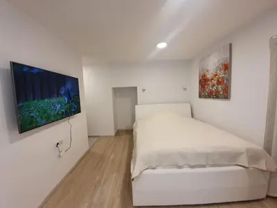 a white bedroom with a bed and a painting on the wall at Studio Apartment Gea 2 Tour As Ljubljana in Ljubljana