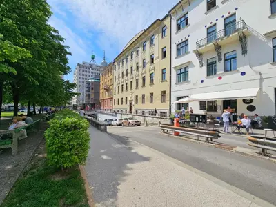 people sitting on benches on a city street with buildings at Studio Apartment Gea 2 Tour As Ljubljana in Ljubljana