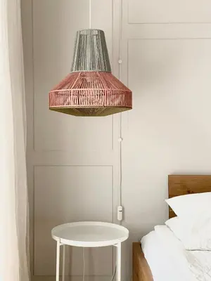 a pink pendant light above a white table next to a bed at Studio XII in Bled