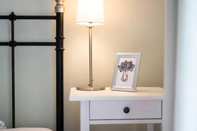 a bedside table with a lamp and a picture on it at Alpine apartments Marcella in Žirovnica