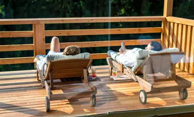 two people laying in rocking chairs on a deck at Apartmaji na kozolcu - Smogavc in Zreče