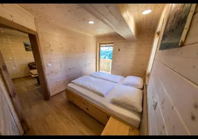 a small room with a bed in a wooden cabin at Apartmaji na kozolcu - Smogavc in Zreče
