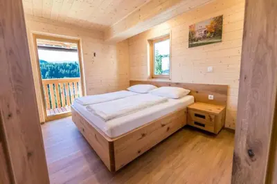 a bedroom with a bed in a wooden cabin at Apartmaji na kozolcu - Smogavc in Zreče