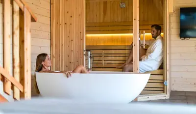 a man and a woman sitting in a bath tub at Apartmaji na kozolcu - Smogavc in Zreče